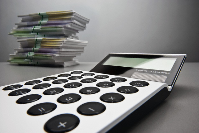 Image of calculator beside stacks of money